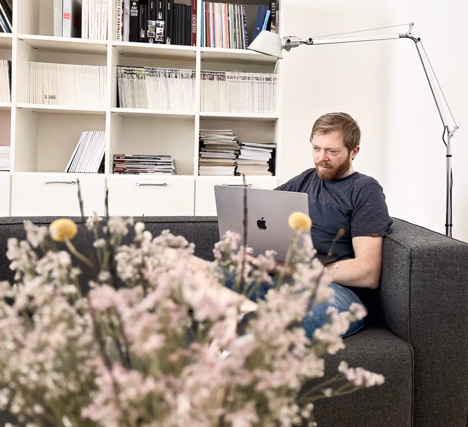 Person mit Laptop sitzt auf Sofa