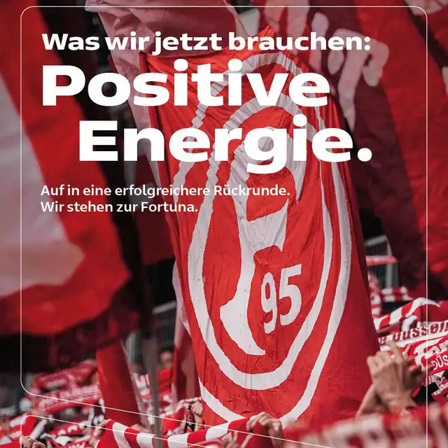 Fans mit F95-Schals und -Flaggen; darüber der Text "Was wir jetzt brauchen: Positive Energie."