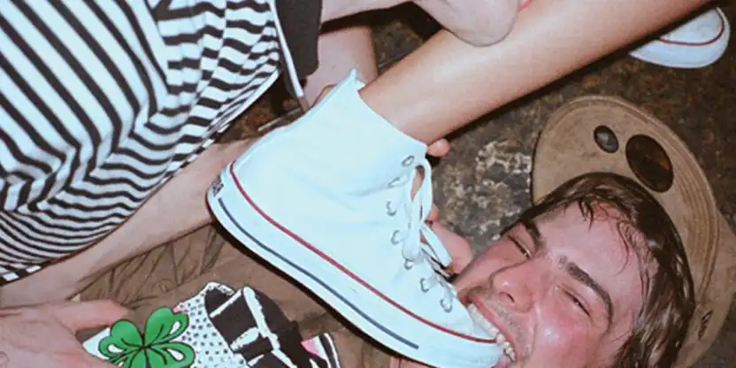 Junger Mann beißt in einen Turnschuh