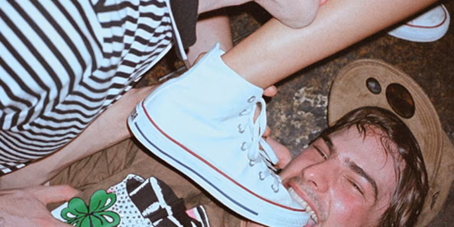 Junger Mann beißt in einen Turnschuh